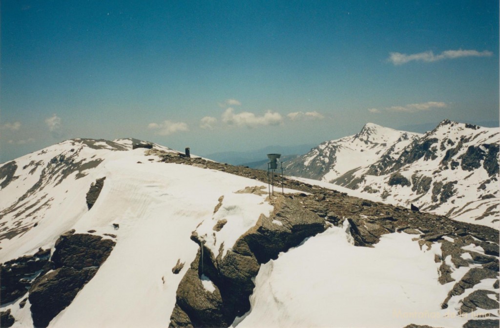 Delante la chimenea y tejado del Refugio Elorrieta, detrás a la izquierda el Pico del Tajo de Los Machos y a la derecha el Caballo